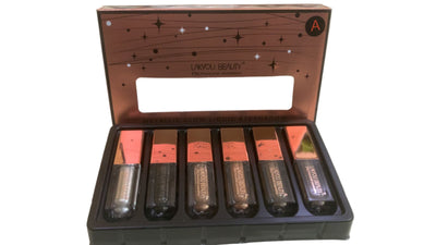 Makeup set with lipsticks and a mirror in an open box on a white surface.